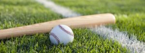 A selective focus view of a baseball bat and ball on the grass near a field stripe